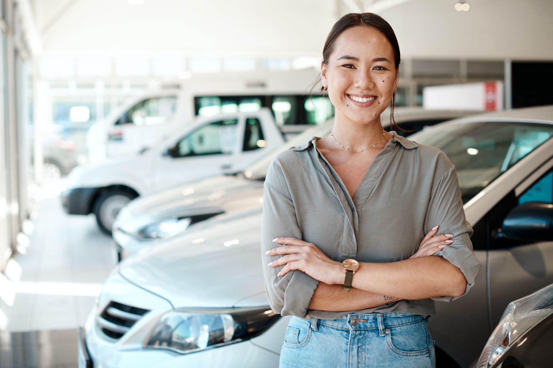 Shot of a young woman standing next to the car she's about to buy